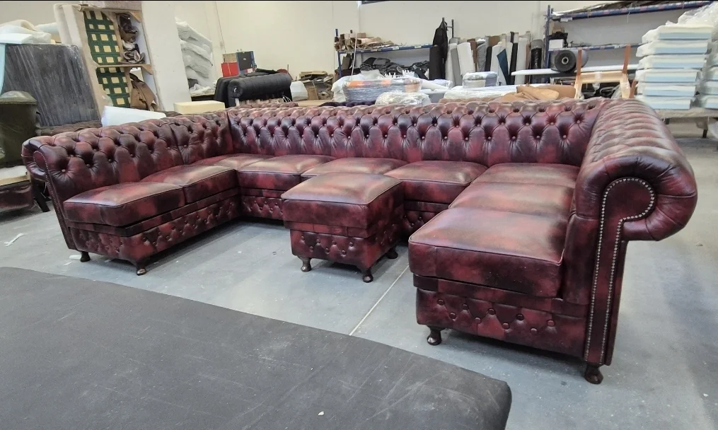 Bordowa sofa Chesterfield z pufami w trakcie wykonania w warsztacie